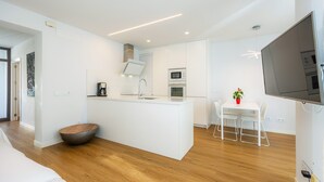 Una cocina moderna con armarios blancos, una isla central y un comedor con mesa y sillas.