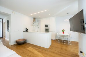Une cuisine moderne avec des meubles blancs, un îlot central et un coin repas comprenant une table et des chaises.