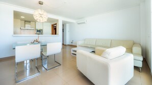 A modern living room with a white sofa, a glass dining table with chairs, and a pendant light. - Minimal Apartment Ref 9000 with Sea View, Balcony, Wi-Fi and Air Conditioning (Can Picafort)