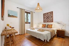 A bedroom with a bed, bedside table, lamp, and a window with curtains. - Vacation Home "Casa La Bubilla en Lajares" with Private Garden & Wi-Fi (Lajares)