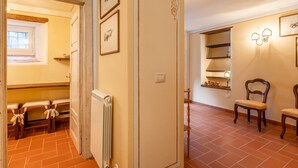 A hallway with a radiator, a door with a decorative frame, and a chair.