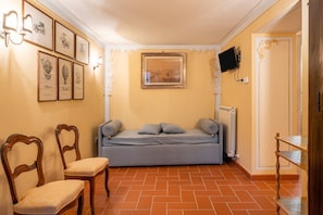 A room with a bed, chairs, a TV, and framed pictures on the wall. - Holiday Apartment "Grillo Rosso Taverna" with Fireplace (Molazzana)