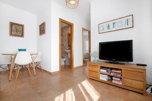 Un soggiorno moderno con televisore, mobile contenitore in legno e zona pranzo.