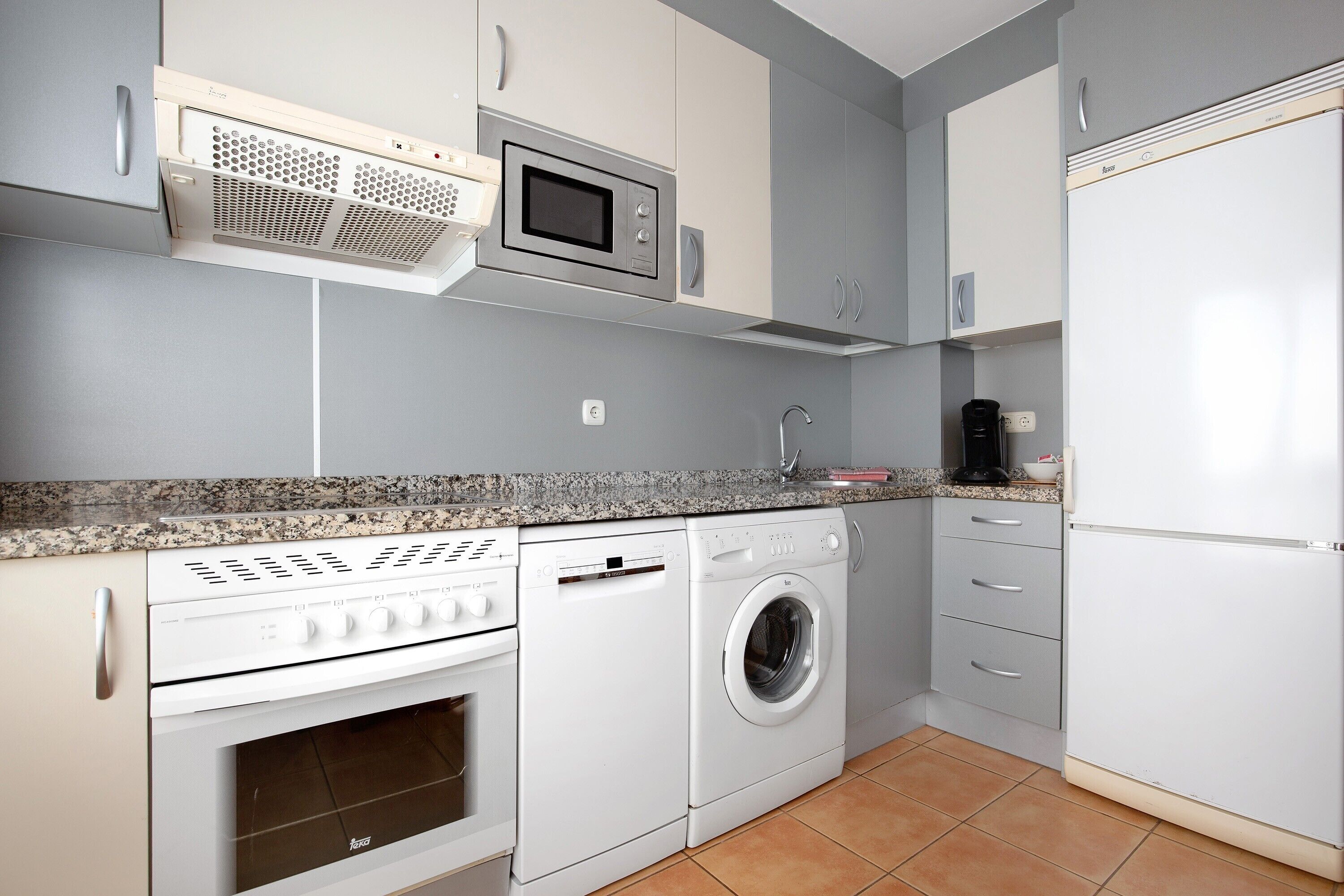 Una cocina equipada con microondas, horno, lavadora y refrigerador.