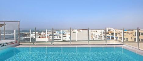 Una piscina amb vistes a edificis i al mar.