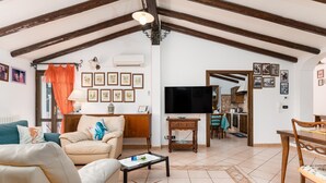 Ein Wohnzimmer mit Sofa, Couchtisch, Fernseher und einer Küche im Hintergrund.