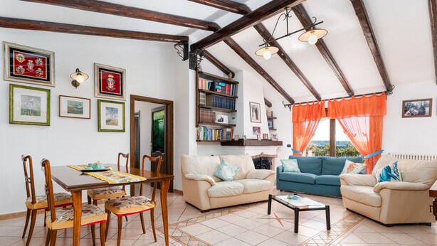 Ein Wohnzimmer mit Esstisch, Stühlen, Sofas, einem Couchtisch und einem Bücherregal.