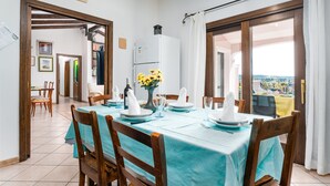 Ein Esszimmer mit Tisch für vier Personen, einem Kühlschrank und Blick durch die Tür.