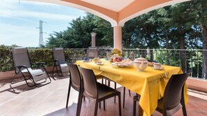 Eine Terrassengruppe im Freien mit gelbem Tischlein, Stühlen und einem für das Frühstück gedeckten Tisch.
