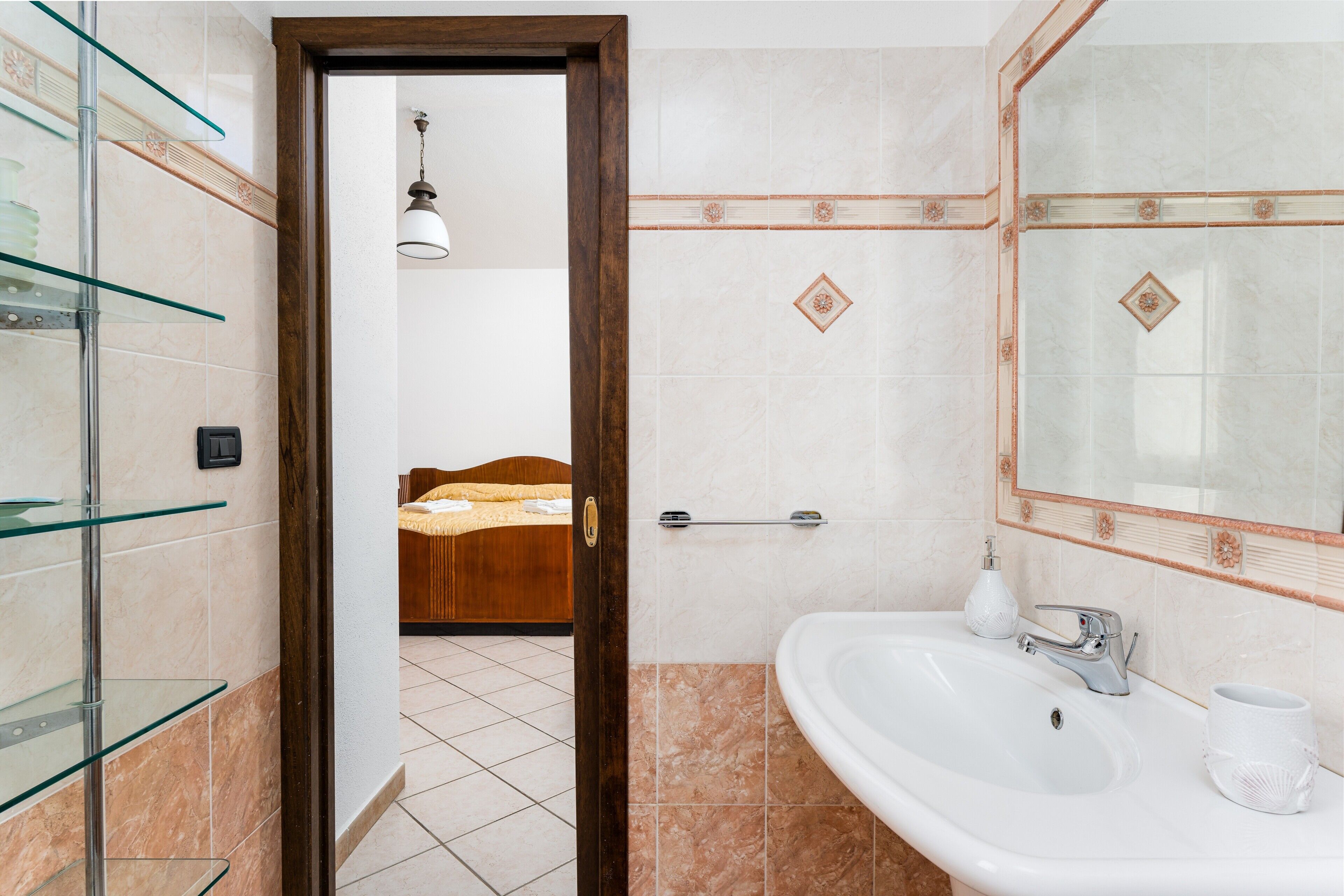 A bathroom with a white sink, a mirror, and a glass shower enclosure.