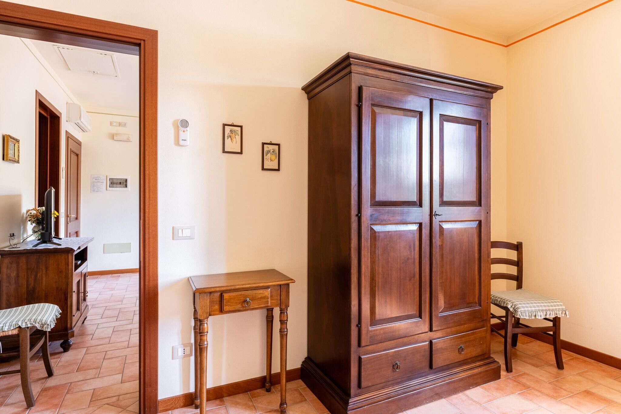 Une pièce comprenant un meuble en bois, une petite table, une chaise et une porte donnant sur une autre pièce.