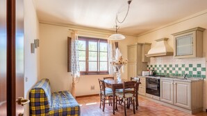 A kitchen with a dining table, chairs, a chandelier, and a window with curtains. - Holiday Home "Mughetto" with Shared Pool, Terrace and Wi-Fi (montecarlo)