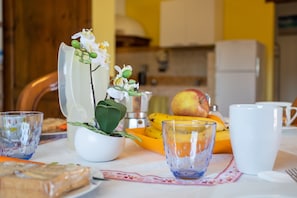 A dining table with a white tablecloth, a potted plant, a fruit bowl, and a white mug.
