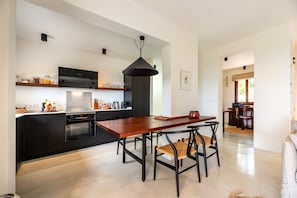 A modern kitchen with a central island, black cabinetry, and a pendant light.