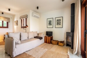 Una sala de estar acogedora con un sofá, televisión, chimenea y obras de arte enmarcadas en la pared.