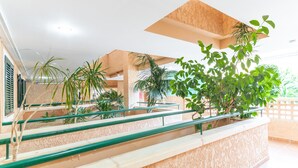 A staircase with green railings, surrounded by potted plants and a beige wall.