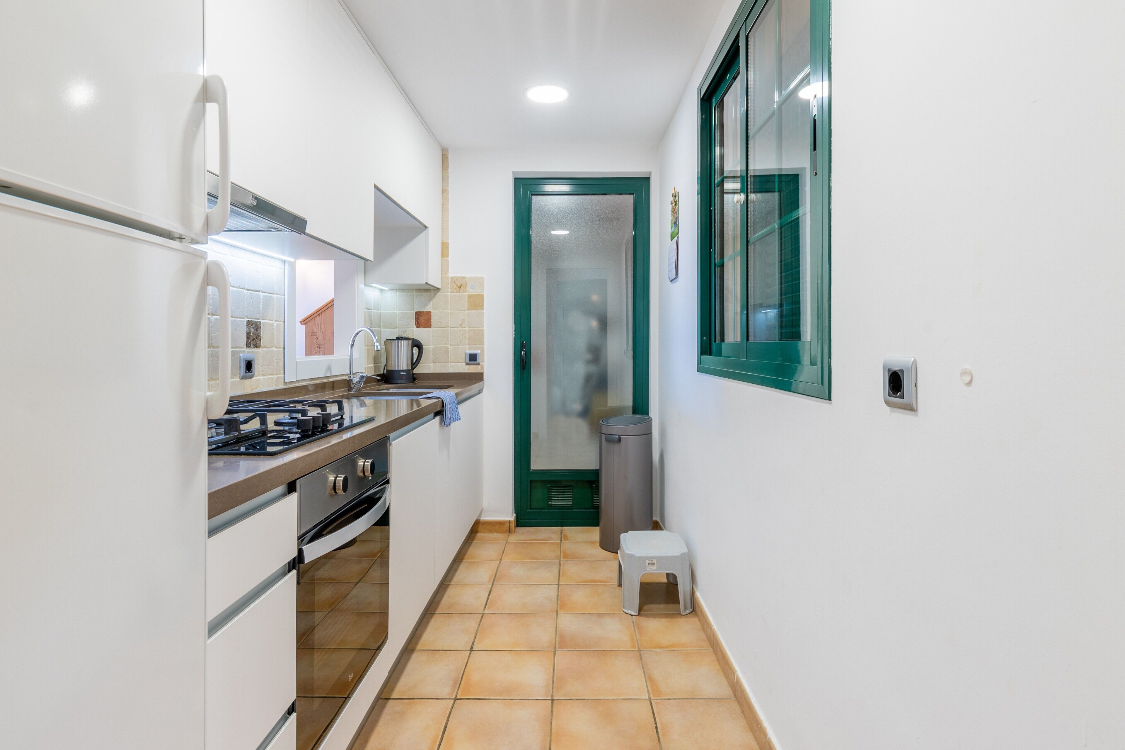 Una cocina estrecha con estufa, horno y refrigerador.