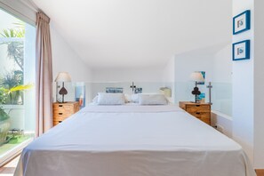 Quarto com uma cama grande, duas mesas de cabeceira, janela com cortinas e vista para o verde lá fora.
