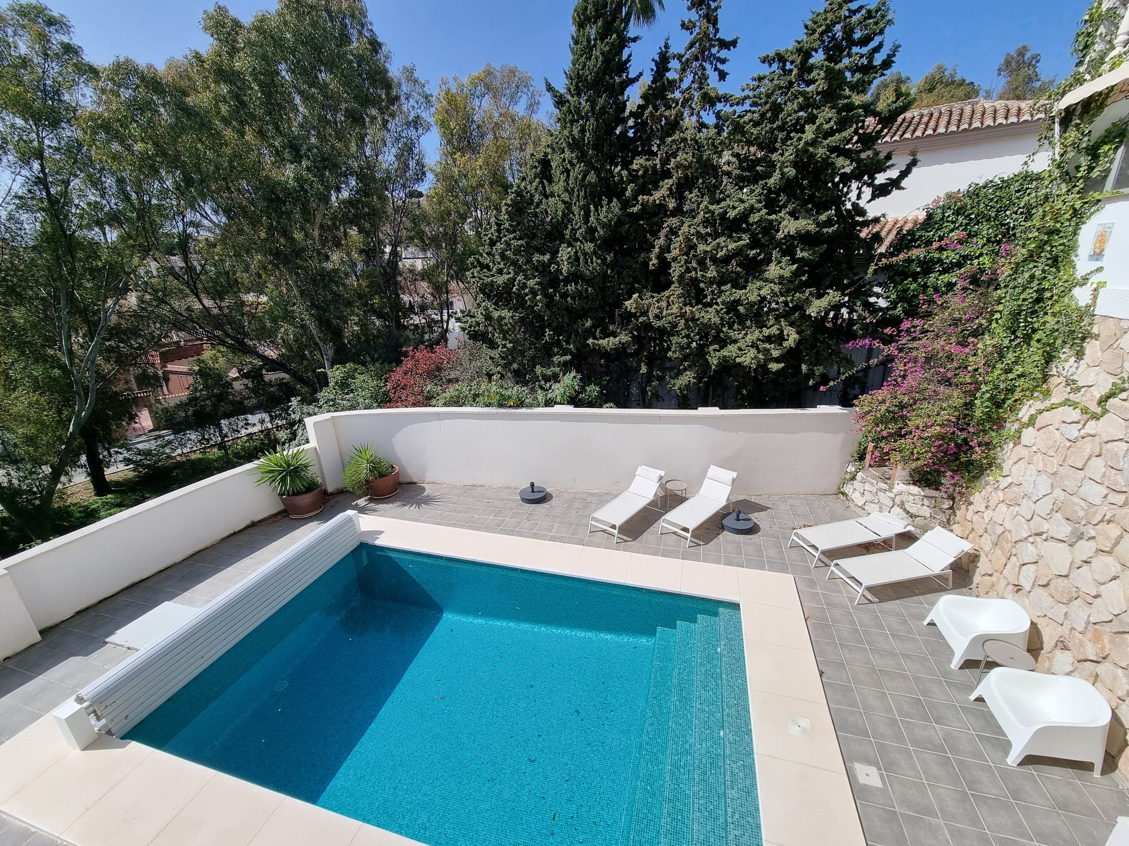 Une piscine avec des chaises longues et des plantes en pot.