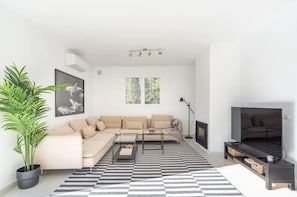 Ein modernes Wohnzimmer mit einer Couch, Couchtisch, Fernseher und einem gemusterten Teppich.