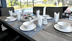 Een eettafel gedekt voor vier personen, met witte borden, kommen en kopjes, plus een dienblad met servetten.