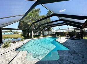 Une piscine extérieure couverte, avec un bassin aux eaux d’un bleu limpide, entourée d’une terrasse dallée et d’une structure en métal.