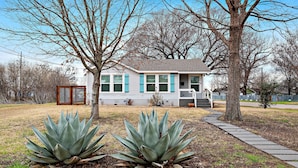 Una casa con un giardino anteriore, un vialetto e due piante di agave.