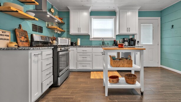 Una cucina moderna con mobili bianchi, un piano di lavoro in legno e un piano cottura integrato.