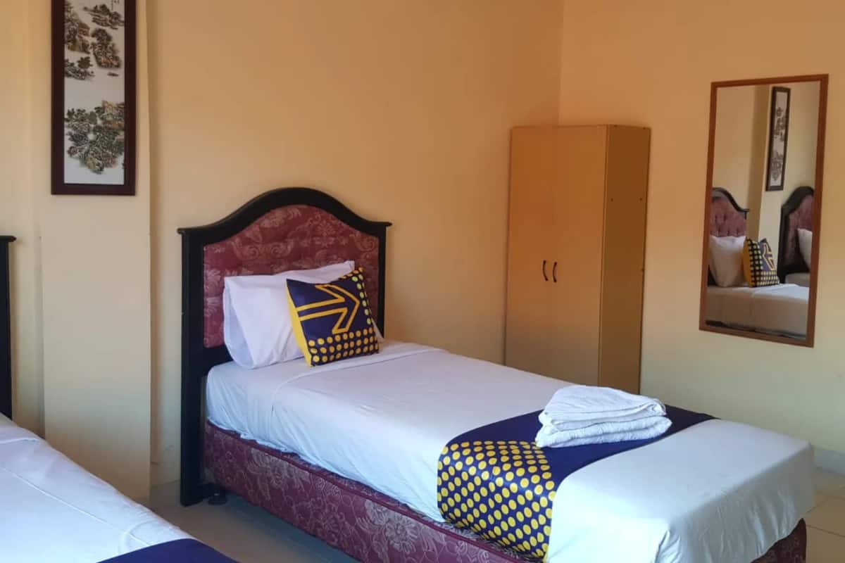 Une chambre d’hôtel avec un lit, une armoire, un miroir et une œuvre d’art encadrée accrochée au mur.