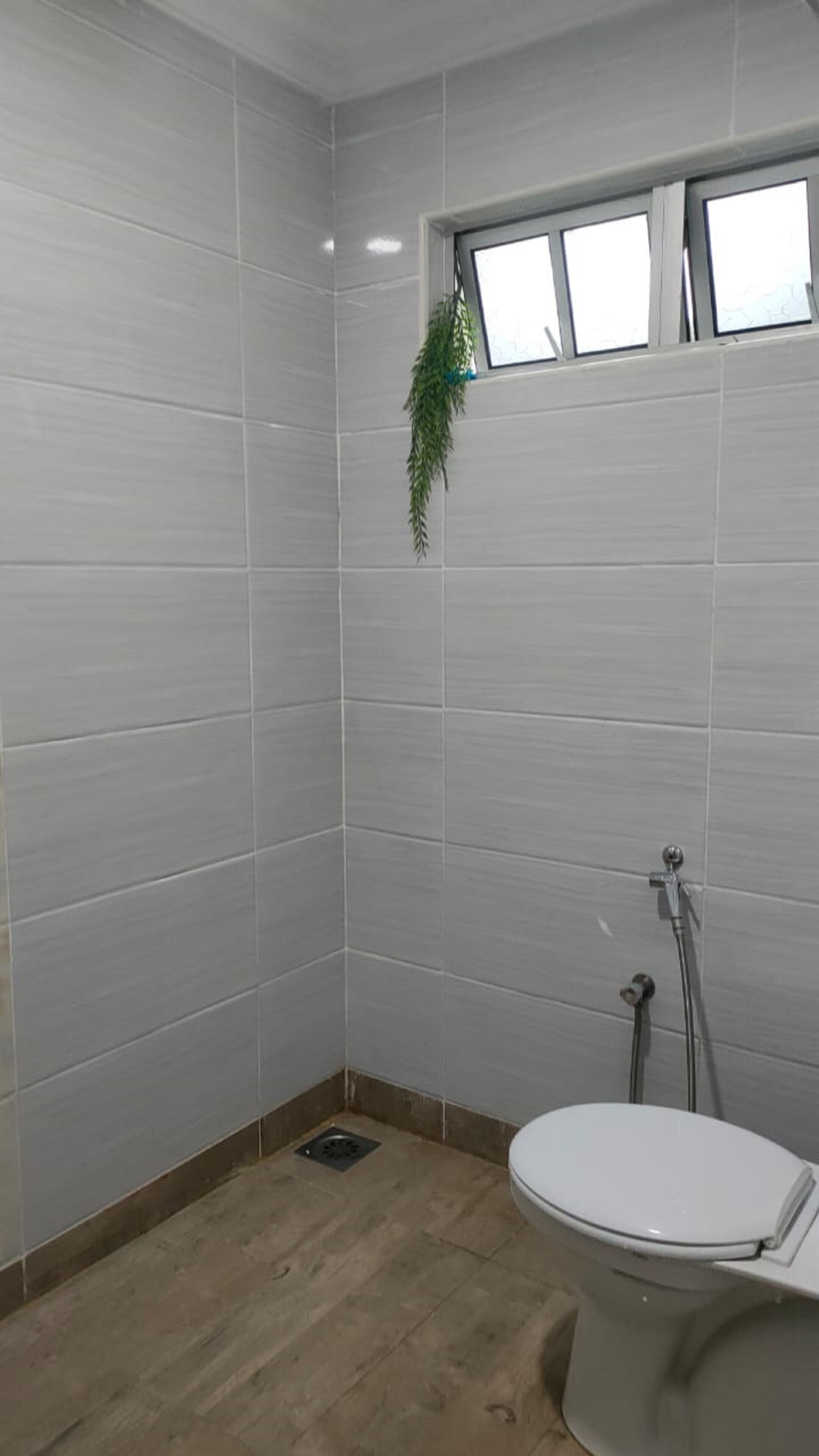 A small, enclosed shower area with a toilet and a window.