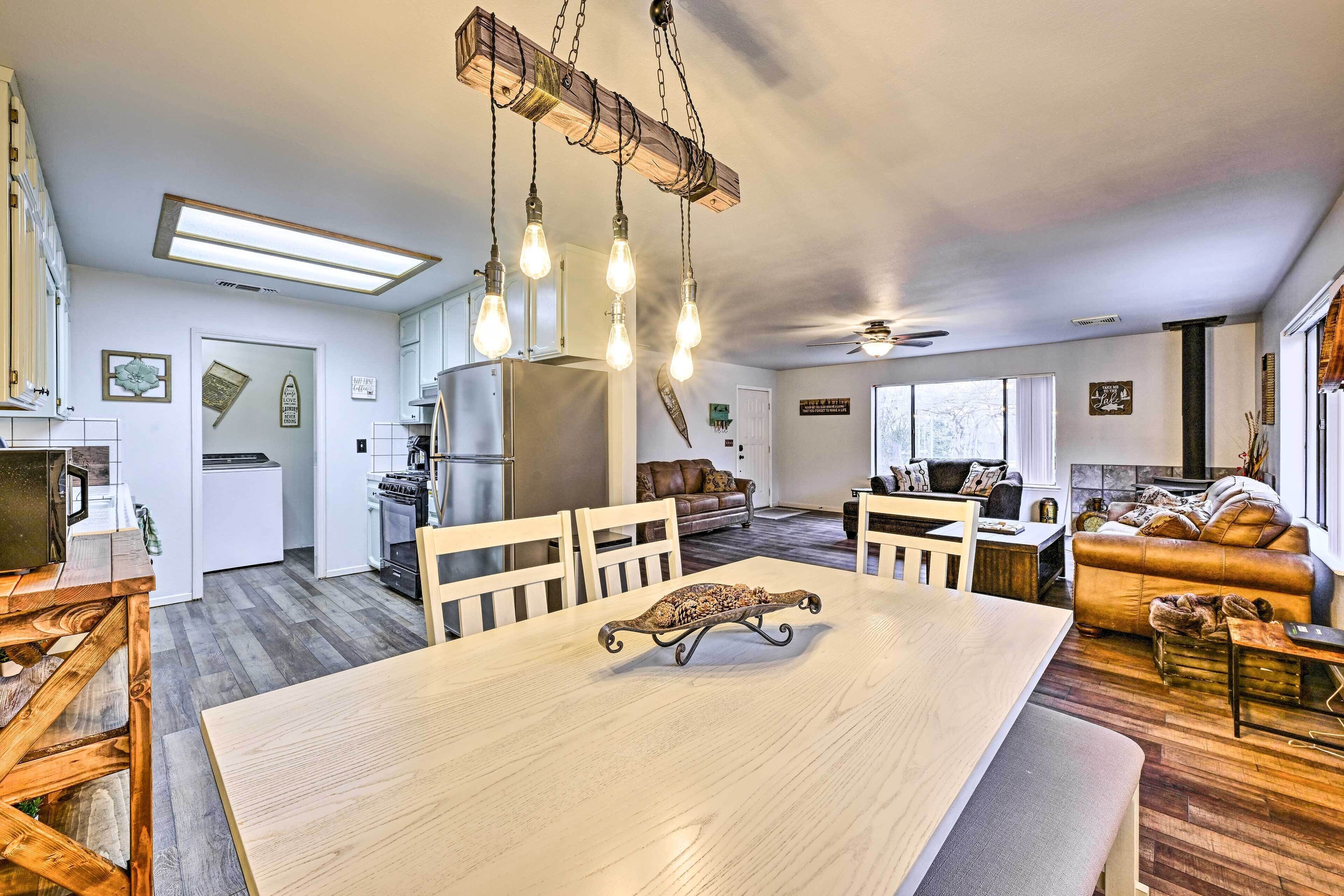 A spacious living area with a large wooden dining table, a sofa, and a kitchen in the background.