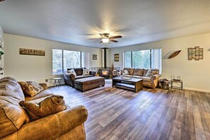 Ein geräumiges Wohnzimmer mit Deckenventilator, zwei Sofas, einem Couchtisch und einem Kamin.
