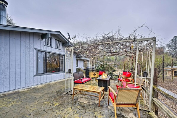 A patio with outdoor furniture, a pergola with string lights, and a building with a chimney.