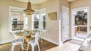 A dining area with a round table, white chairs, and a chandelier. - Sea-rendipity: Pool Access Near Perdido Beaches! (Pensacola)