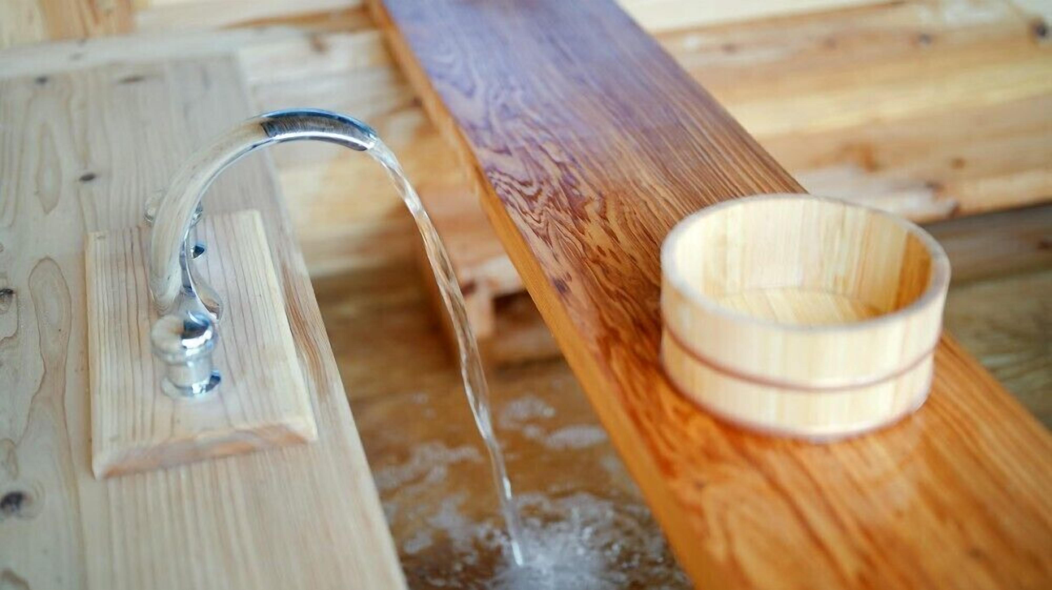 Un banco de madera con un grifo de metal y un cuenco de madera.