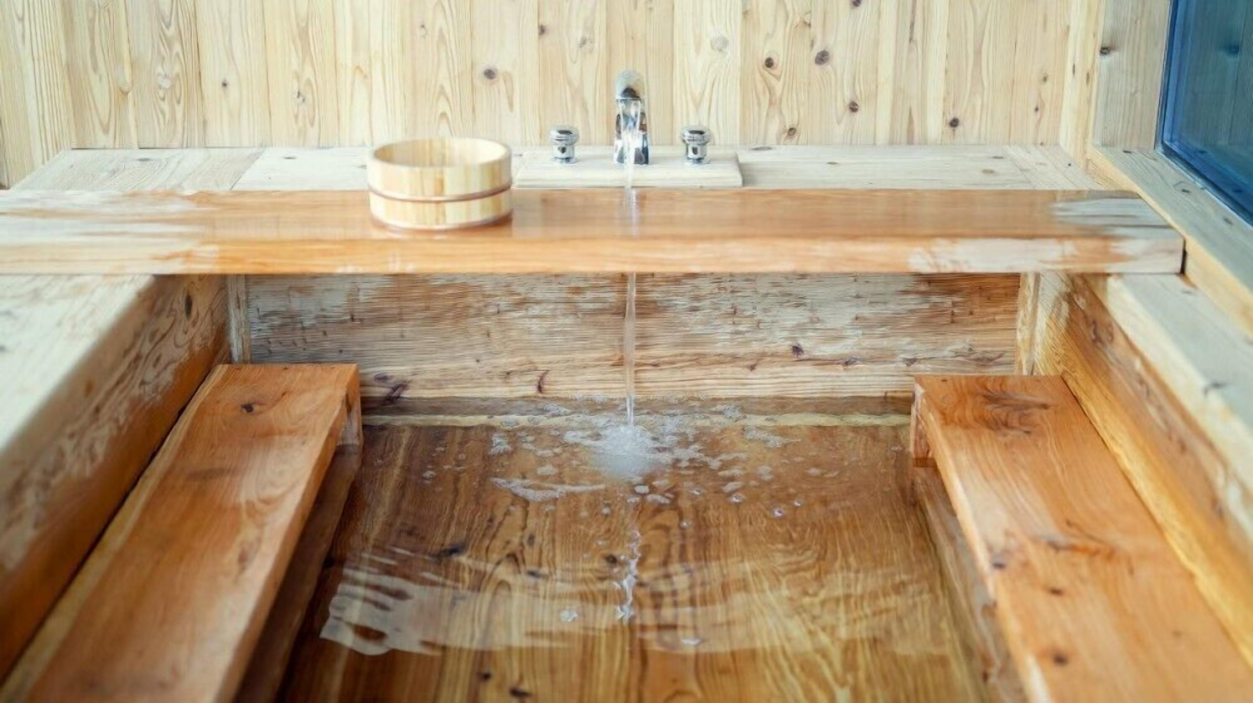 A wooden sauna with a wooden bench and a small wooden bowl on the bench.