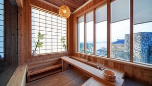 Ein Holzinterieur mit einem großen Fenster, einer hölzernen Bank und einem Tisch mit zwei Gläsern.