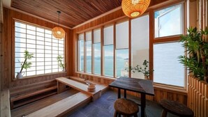 Ein traditioneller japanischer Raum mit Tatami-Boden, einem niedrigen Holztisch und einer Sitzbank.