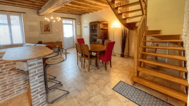 A rustic interior with exposed wooden beams, a dining area with red chairs, and a wooden staircase. - La Bergerie, Meublé de Tourisme*** for 4 people (Pontlevoy)