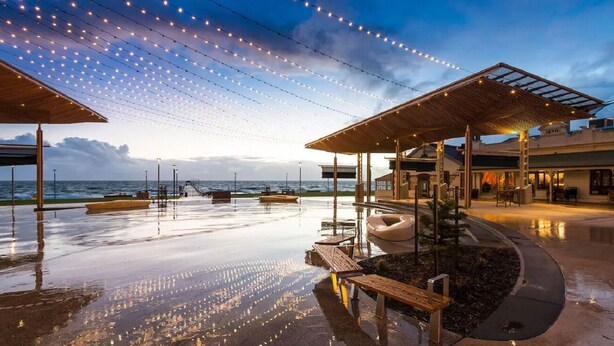 A beachfront resort with outdoor seating, string lights, and a covered area. - The Beach House At Henley (Henley Beach)