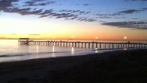 A pier extending into calm waters at sunset. - The Beach House At Henley (Henley Beach)