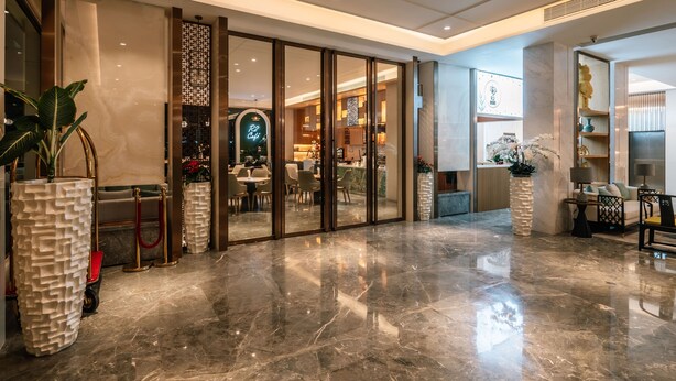 A spacious lobby with a polished marble floor, a reception area with a glass partition, and a seating area with a sofa and a coffee table. - Laike Hotel (Bangkok)