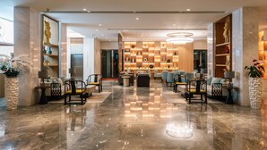 A spacious lobby with a polished marble floor, seating areas, and a decorative wall with geometric patterns. - Laike Hotel (Bangkok)