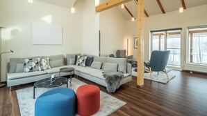 A modern living room with a sofa, ottomans, and a chair.