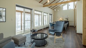 A spacious living area with large windows, a round coffee table, and modern furniture.