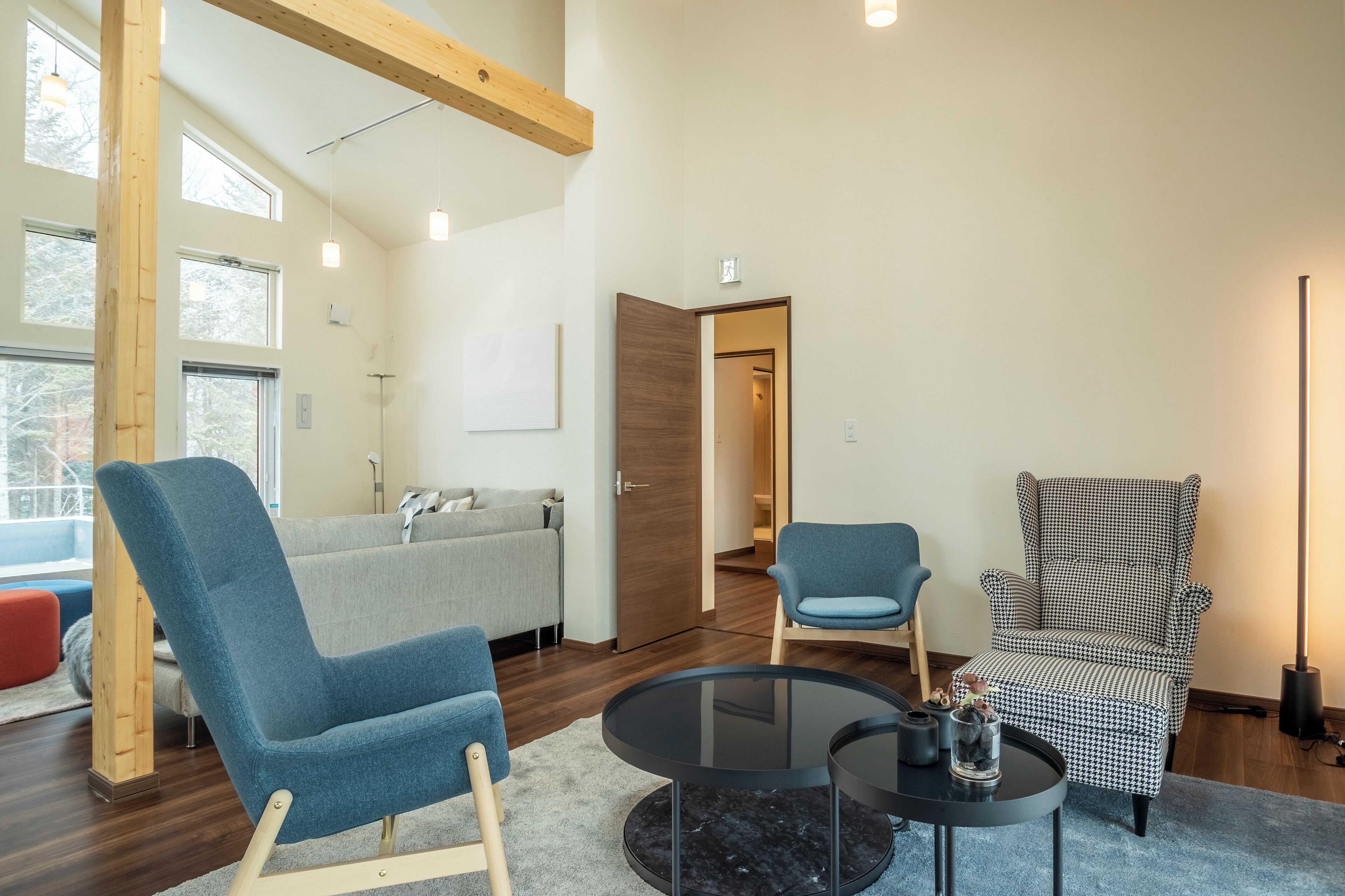 A modern living room with a sofa, two armchairs, a coffee table, and a houndstooth armchair.