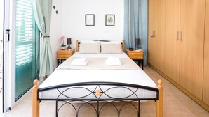 Una cama bien hecha con almohadas y toallas, mesitas de noche de madera con lámparas, un armario y una ventana con cortinas.