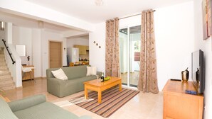 Una sala de estar con sofá, mesa de centro y mueble para televisor.