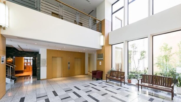Eine geräumige Lobby mit hoher Decke, einer Zwischenebene und großen Fenstern, die für viel Tageslicht sorgen.