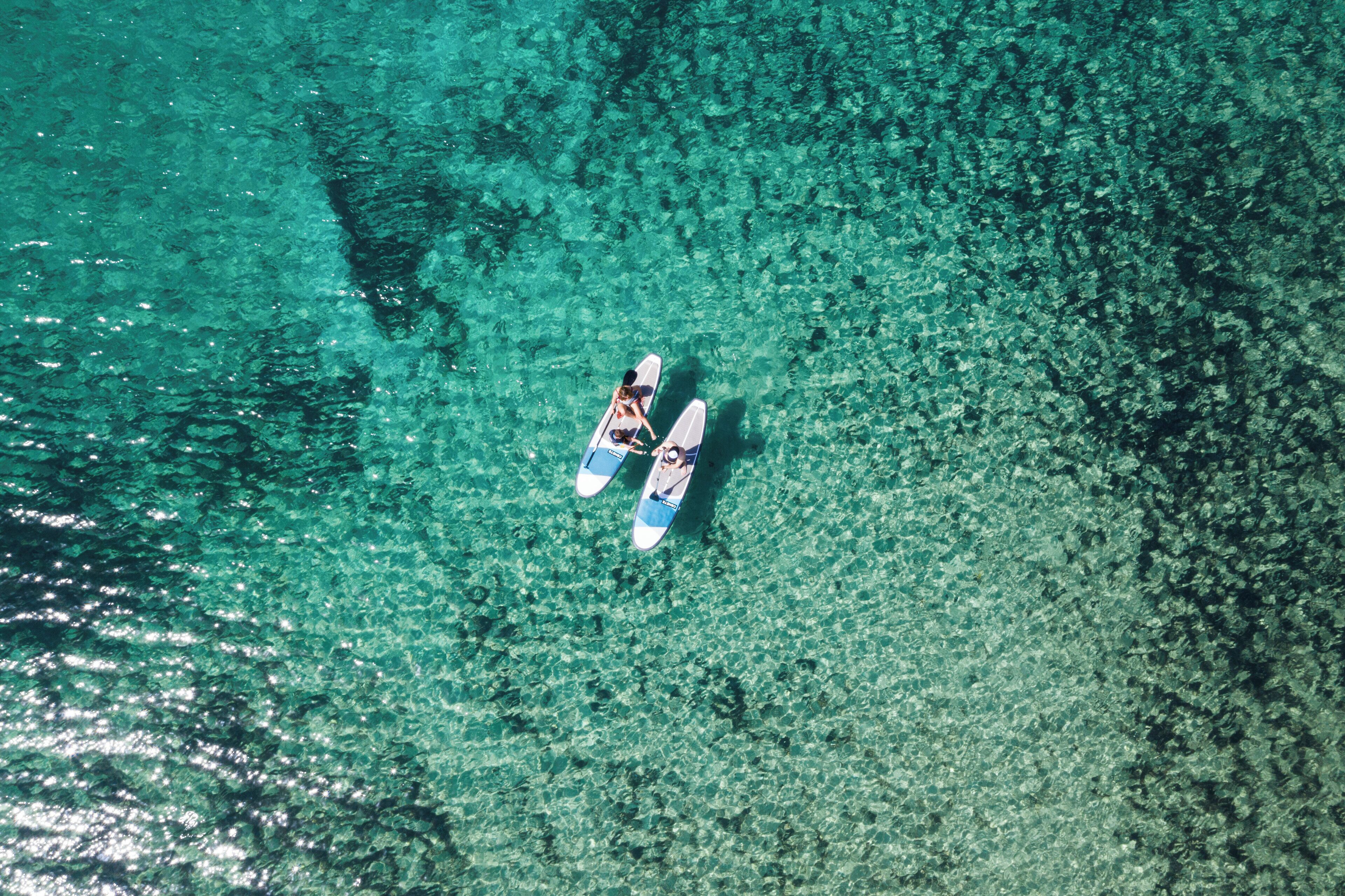 An aerial view of a beach with clear turquoise water and two surfboards.